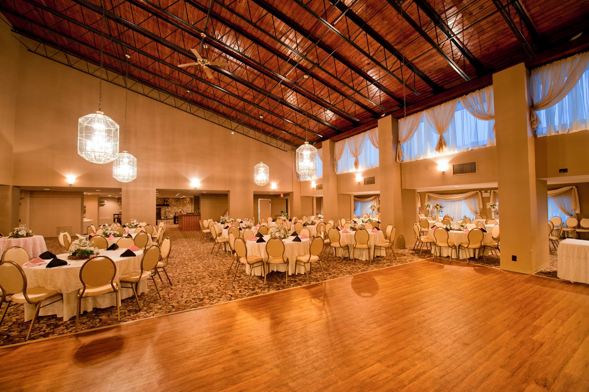 The Candlelite Room with wood ceiling, lantern chandeliers, wood dance floor and round tables set with pink napkins in Delran NJ